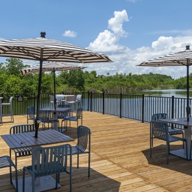a lake lounge area with tables, chairs and umbrellas